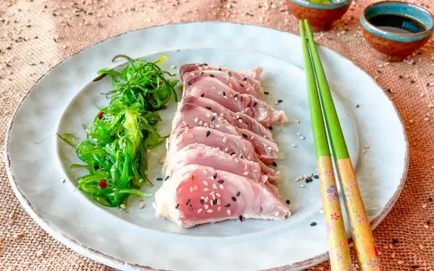 Tataki de bonito, finas lonchas de pescado crudo con semillas de sésamo, acompañadas de ensalada de algas.