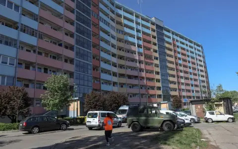 Długi, wielopiętrowy blok mieszkalny, prawdopodobnie najdłuższy blok w Polsce, z kolorowymi balkonami i oknami, na tle błękitnego nieba.