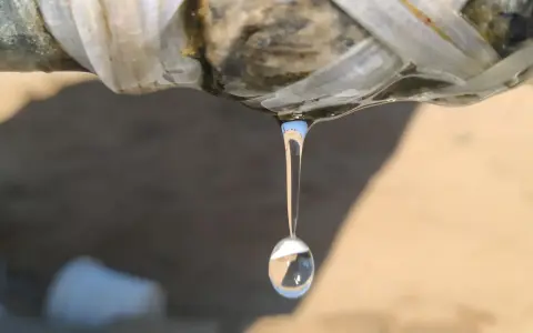 Gota de agua cayendo de una tubería rota, indicando la necesidad de reparar tubería.