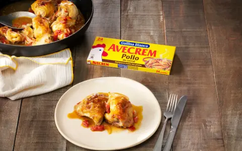 Sabroso pollo con sopa de cebolla y cerveza, servido en sartén y plato. Caja de Avecrem Pollo al lado.
