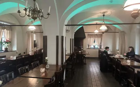 Mysig interiör på Cafe Kronhuset med välvda tak och varma ljus. Två personer sitter vid ett bord och samtalar.