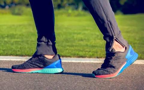 Biegacz stawia kroki, a jego stopa wykonuje ruch supinacji. Kolorowe buty sportowe na bieżni.