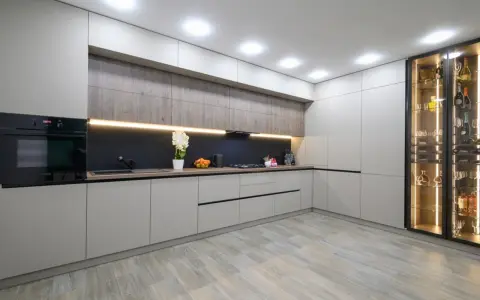 Cocina moderna con armarios grises y vitrina iluminada. El suelo de madera clara es perfecto para suelos para cocinas sin obras, aportando calidez y estilo.