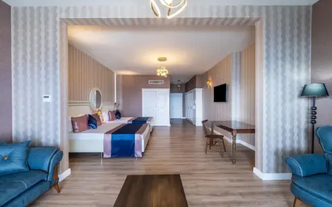 Przytulny pokój w Orange County Resort Alanya z dwoma łóżkami, niebieską sofą i stołem.