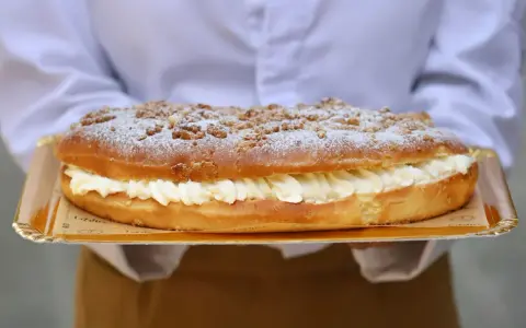 Deliciosa coca de San Juan rellena de crema, cubierta con azúcar glas y trocitos crujientes. ¡Perfecta para celebrar!
