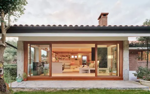 Ristrutturazione esterna di una casa anni '70: un'oasi moderna con ampie vetrate che si aprono sul verde.