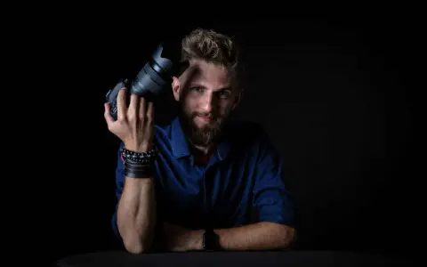 Mężczyzna z aparatem fotograficznym, gotowy do rozpoczęcia kursu fotografii.
