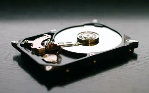 Odsłonięty dysk twardy w laptopie, z błyszczącym talerzem i ramieniem odczytującym dane.