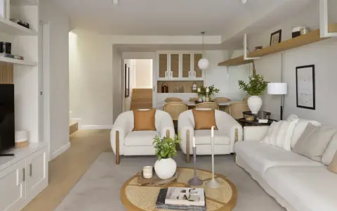 Salón rectangular dos ambientes con sofás blancos, sillones de borrego y mesa de centro de ratán.