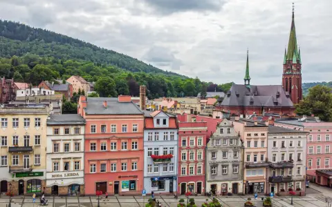 Kolorowe kamienice i kościół z zieloną wieżą tworzą malowniczy widok. Odkryj teraza ruda atrakcje!