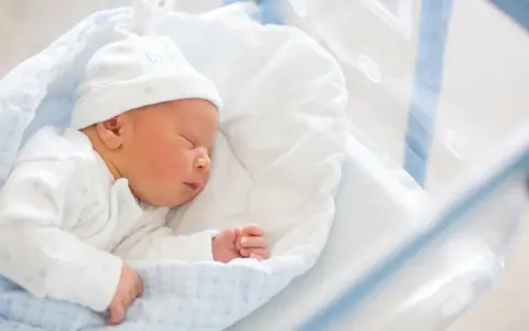 Śpiący noworodek w czepku z napisem "DADDY". To idealny moment na becikowe dla kogoś tak małego.
