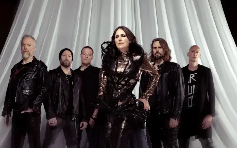 Within Temptation Sverige: Sharon den Adel i sin glittrande klänning, omgiven av bandmedlemmar i mörka kläder, framför en vit draperad bakgrund.
