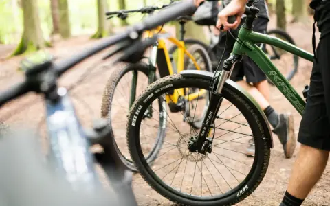 Przygotowania do amatorskich rajdów rowerowych w lesie. Dwa rowery górskie, jeden zielony, drugi żółty, stoją na leśnej ścieżce.