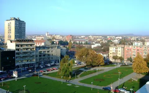 Widok na centrum Kragujevac Serbia z budynkami mieszkalnymi, parkiem i ulicą pełną samochodów.