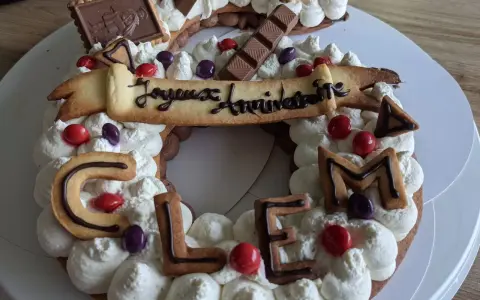 Gâteau d'anniversaire en forme de chiffres, décoré de crème fouettée, de biscuits lettres formant "CLEM", de chocolats et de bonbons. Quelle crème pour recouvrir un gâteau ? Celle-ci est parfaite !