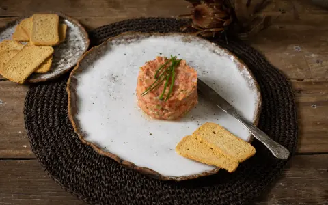Delicioso tartar de tomate, servido con tostas crujientes y un cuchillo de plata. Un plato fresco y vibrante.