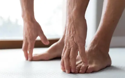 Manos tocando los dedos de los pies, como si sintiera las rampas en los pies.