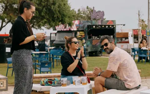 Amigos disfrutan del ambiente de rock en Valencia, con food trucks y música de fondo.