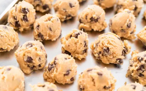 Boules de pâte à cookie au chocolat sur une plaque. Combien de temps la pâte à cookie au frigo se conserve-t-elle ?