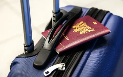 Bagaż rejestrowany Pegasus Airlines gotowy do podróży. Paszporty leżą na niebieskiej walizce, czekając na odprawę.