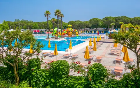 Słoneczny dzień w Portofelice Camping Village. Baseny, zjeżdżalnie i leżaki czekają na gości.