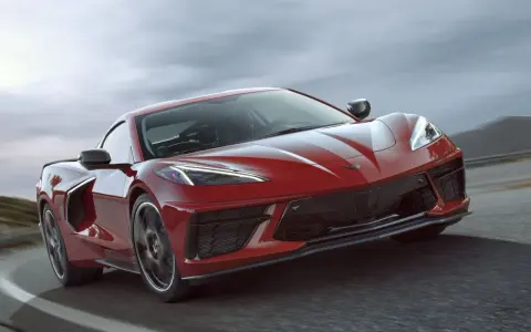 Czerwony Chevrolet Corvette C8 pędzi po drodze, jego sportowy design podkreślony przez dynamiczne linie i agresywny przód.