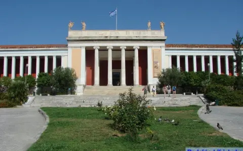 Narodowe Muzeum Archeologiczne w Atenach, z grecką flagą na dachu, zaprasza zwiedzających.
