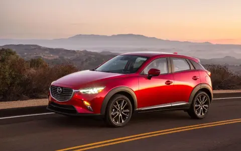 Czerwona Mazda CX-3 na tle górskiego krajobrazu o zachodzie słońca. Elegancka linia nadwozia i lśniący lakier.