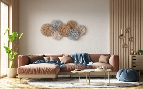 Decoración pared salón original con un sofá terracota y arte de pared circular en tonos dorados y plateados.
