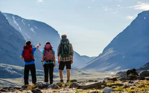 Vandrare med ryggsäckar njuter av den storslagna utsikten över fjällen under en abisko sommar.