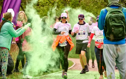 Uczestnicy biegu w kolorowym proszku, w tym 3 forma run, biegną wśród zielonej chmury.