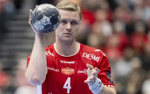 Aron Palmarsson, zawodnik z numerem 4 na czerwonej koszulce, trzyma piłkę do piłki ręcznej, gotowy do rzutu.