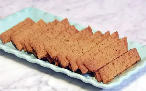 Raka, gyllene kolasnittar med choklad, uppradade på en ljusblå bricka. Perfekta för fikat!