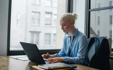 Donna bionda lavora al laptop, analizzando dati per ottimizzare lo stipendio dell'e-commerce manager.