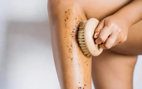 Exfoliación corporal con un cepillo de madera y un scrub para ayudar a como hidratar la piel desde dentro.