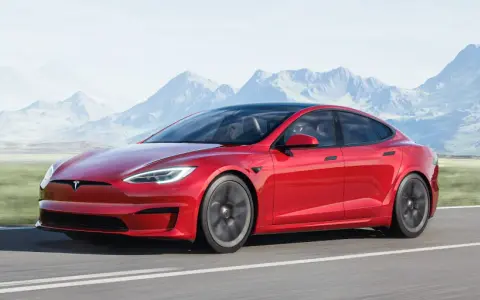 Czerwony Tesla Model S jedzie po drodze, a w tle widać góry. Tesla co to? To przyszłość motoryzacji.