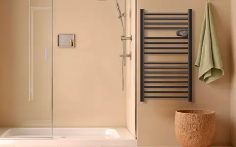 Salle de bain moderne avec douche, porte-serviettes chauffant noir et panier en liège. Le disjoncteur du sèche serviette est visible.