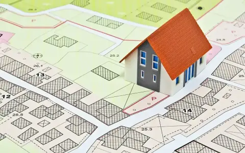 Model domu na tle mapy z zaznaczonymi działkami i oznaczeniami. To wizualizacja miejscowych planów zagospodarowania przestrzennego.
