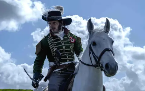 Un officier à cheval, sabre à la main, dans son uniforme vert et son chapeau à panache, incarne le dernier panache histoire.