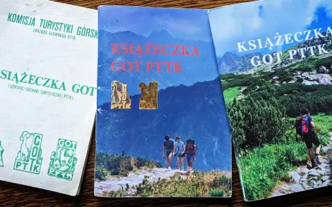Trzy książeczki GOT PTTK z odznakami. Jedna biała z zielonymi symbolami, dwie z górskimi krajobrazami.
