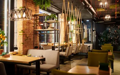 Un restaurante moderno con ladrillo visto, plantas colgantes y columpios. Un lugar acogedor que inspira lo que se necesita para abrir un restaurante.