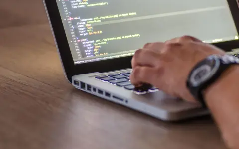 Dłoń pisze kod CSS, optymalizując pliki do wersji min.