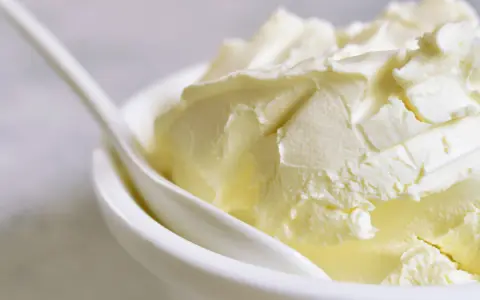 Kremowa masa w białej miseczce, idealna jako zamiennik mascarpone do deserów.
