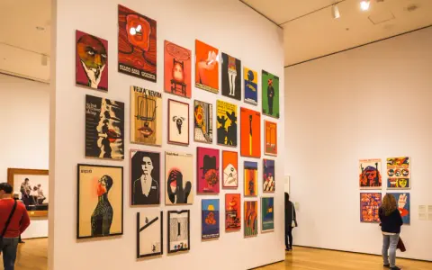 Vibrant posters adorn a gallery wall, showcasing diverse graphic design. This exhibition highlights some of the best art cities in the US.