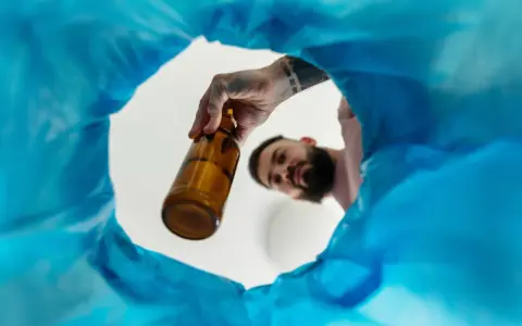 Mężczyzna wyrzuca butelkę, symbolizując wolność i nowe życie bez alkoholu.
