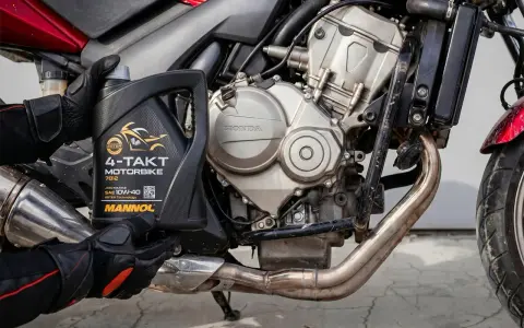 Rękawice motocyklisty trzymają olej Mannol 4-Takt Motorbike SAE 10W-40. Jaki olej do motocykla? Ten zapewni płynną pracę silnika Honda.