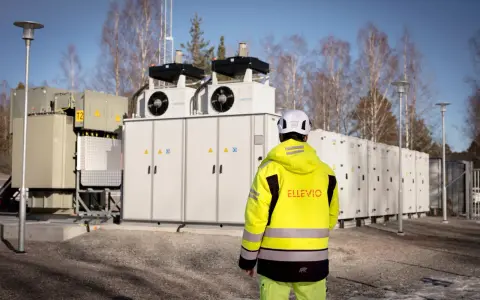 En person i gul jacka står framför en stor fristående batterilagring.