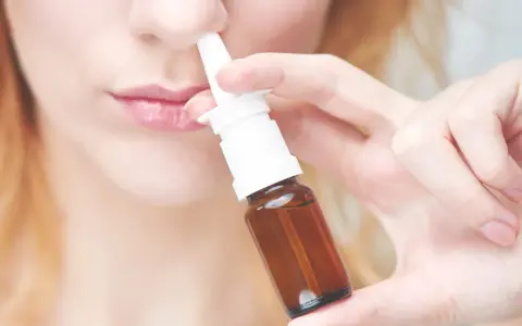 Frau benutzt Nasenspray. Möglicher Geruchsverlust durch Nasenspray.