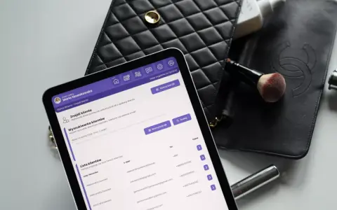 Przykładowa karta klienta salonu kosmetycznego na tablecie, obok czarna kosmetyczka i pędzel do makijażu.
