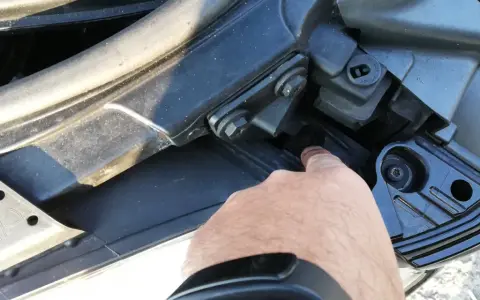 Palec wskazuje śrubę mocującą reflektor podczas wymiany żarówki audi a4 b7 przód prawa.
